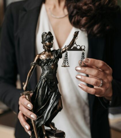 Close-up of Lady Justice statuette held by a lawyer, symbolizing law and justice.
